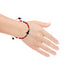 A hand adorned with a Genuine Jet Azabache Red String Bracelet for adults showcases vibrant black, red, and turquoise beads designed for Evil Eye Protection. It includes a cross-shaped black bead and an adjustable red string closure that accentuate the positive energy against a white background.